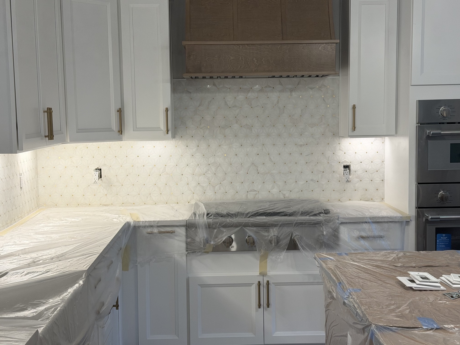 Light mosaic backsplash behind white kitchen cabinets