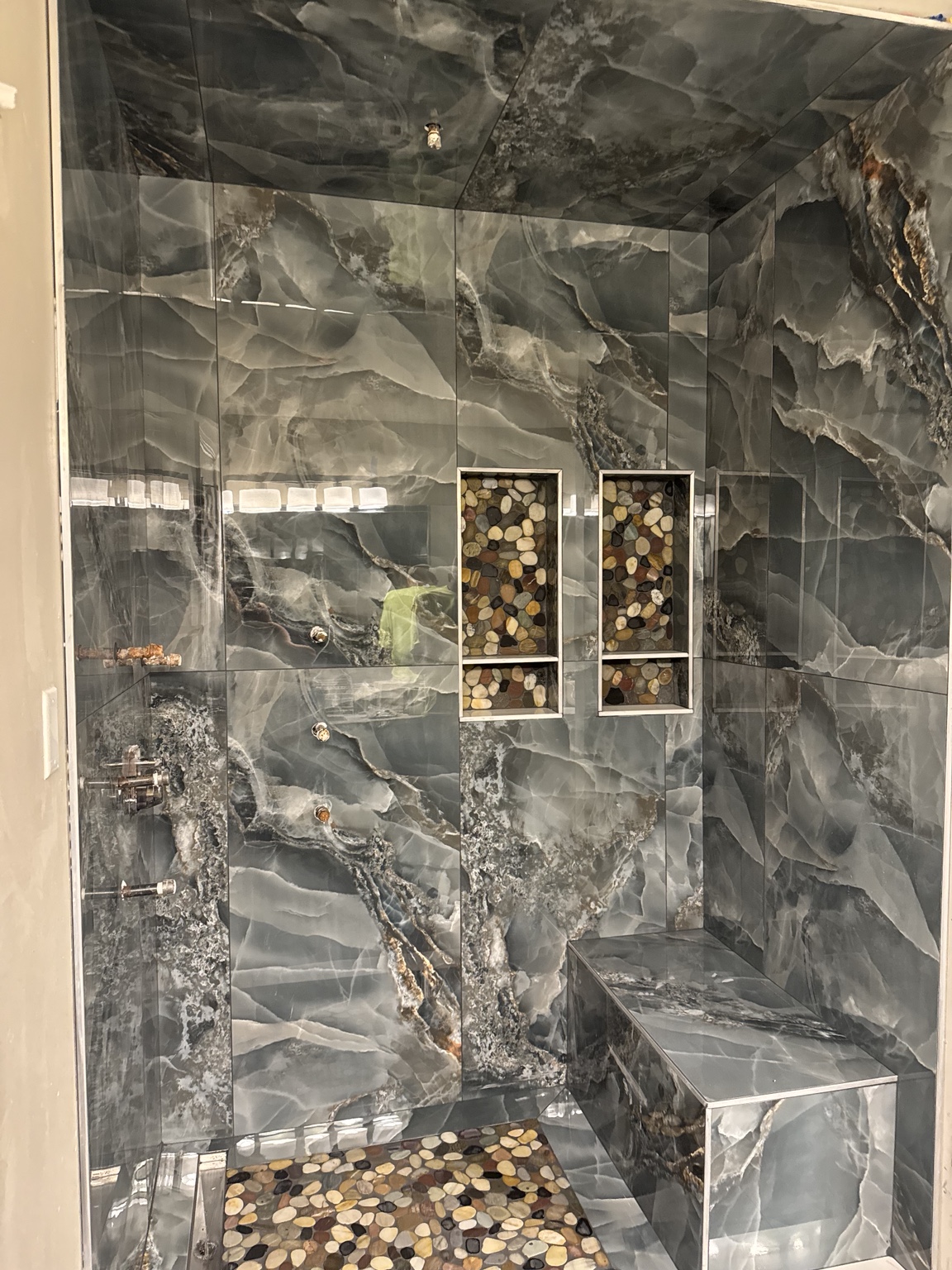 Dark stone-look tile shower with contrasting mosaic niches