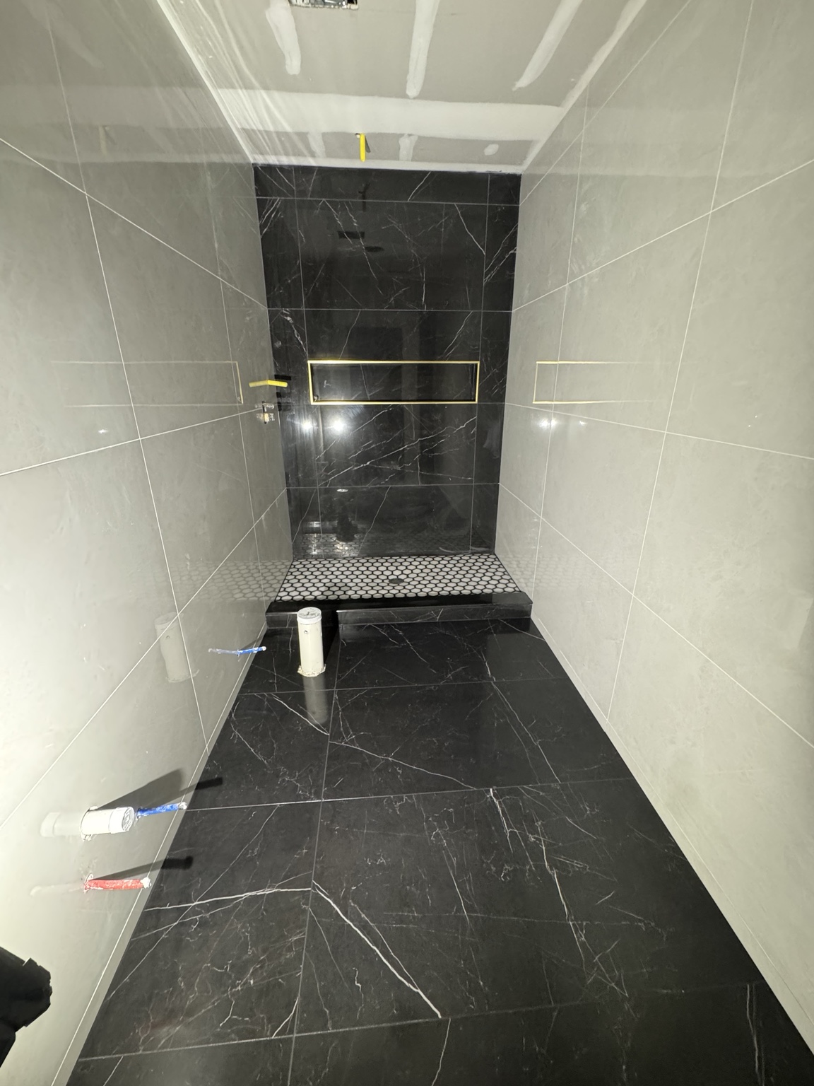 Walk-in shower with light side walls, black accent tile, and a dark floor